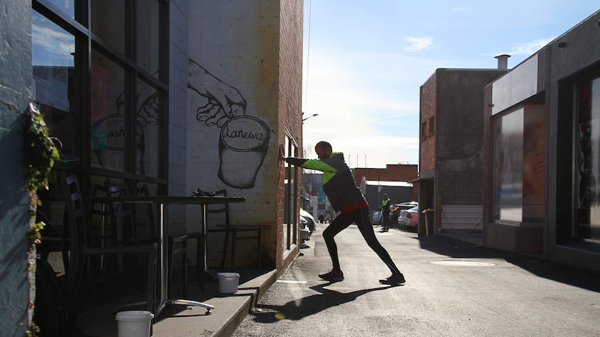 Brian Lyons stretching in a laneway