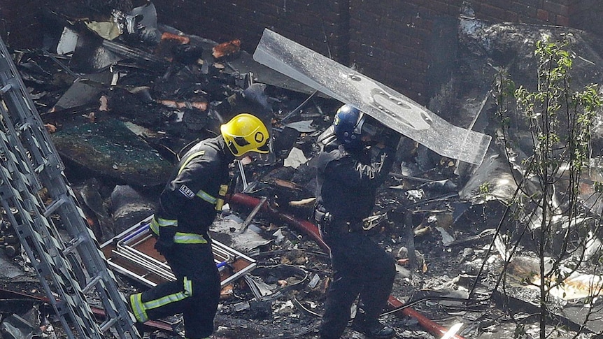 London firefighters walk through debris on ground from Grenfell Tower fire