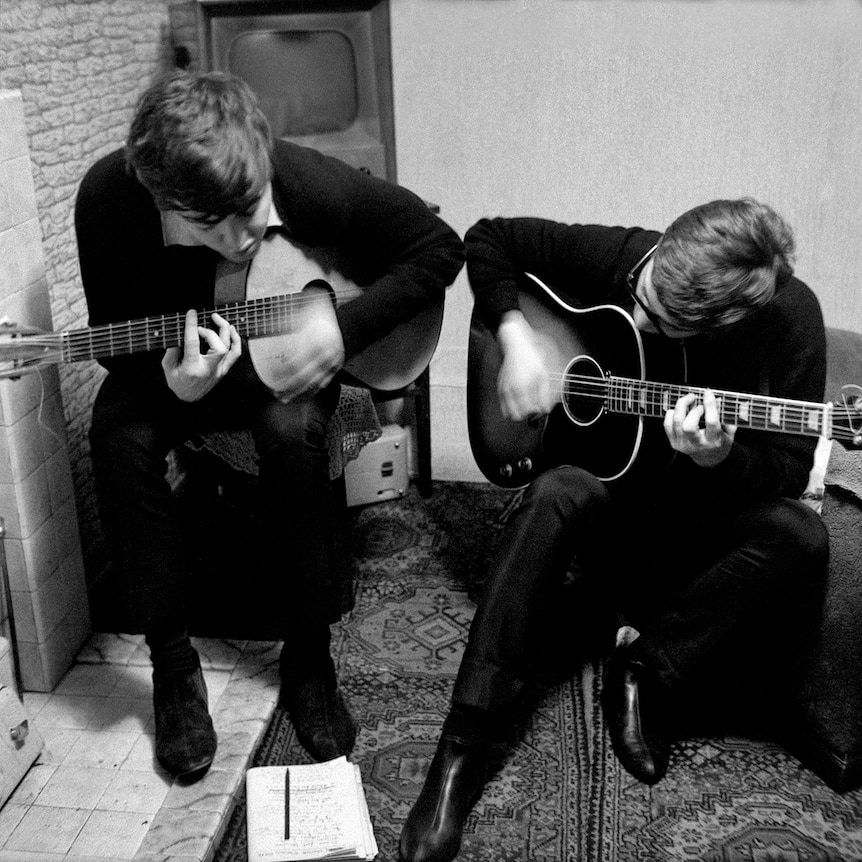 Black and white photo of John Lennon and Paul McCartney playing acoustic guitars