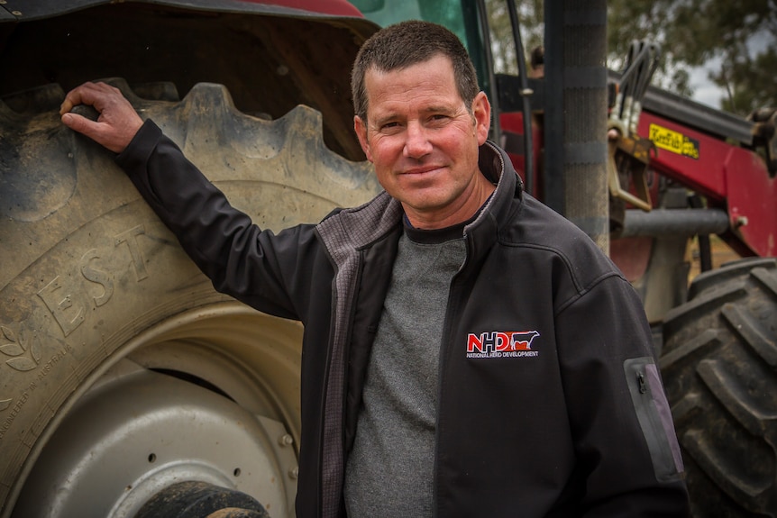 Gary White stands in front of tractors on a farming property in overcast conditions.