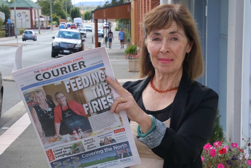 Alison Andrews holds a copy of her newspaper.