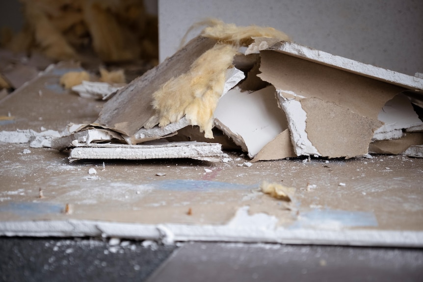 White palsterboard and insulation lay on the floor after falling from the ceiling of an apartment. 