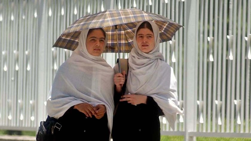 Two Afghan women walk down a street in Kabul