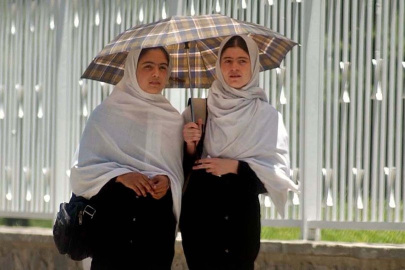 Two Afghan women walk down a street in Kabul