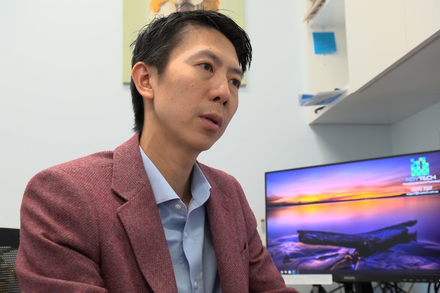 Dr Nick Yim sits at a desk