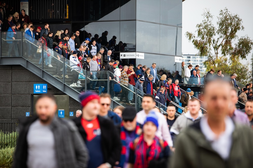 A crowd walking down the stairs at Perth Stadium station. 