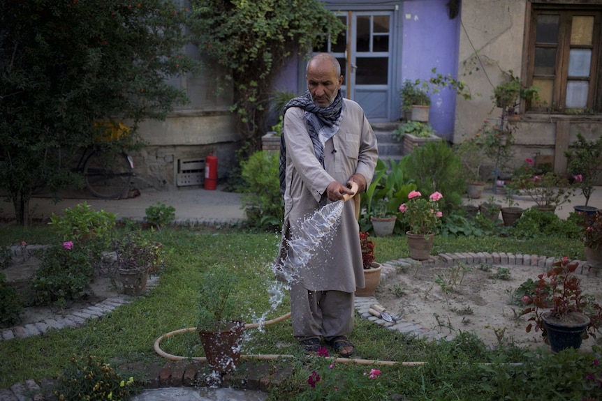 An Afghan man watering his plants in his garden in Kabul.