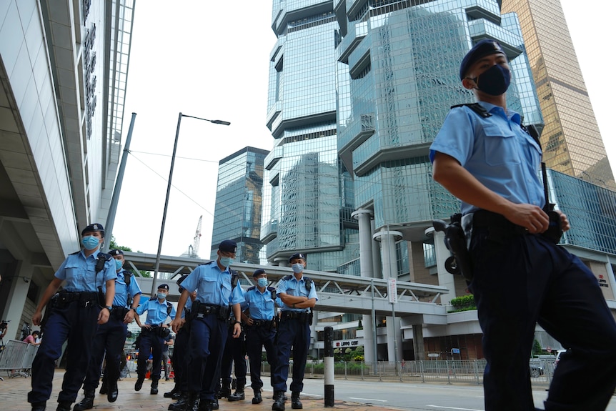 Hong Kong police officers in blue shirts march down the street