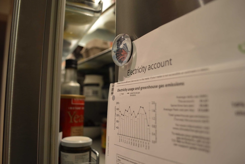 An electricity bill hangs on a fridge.