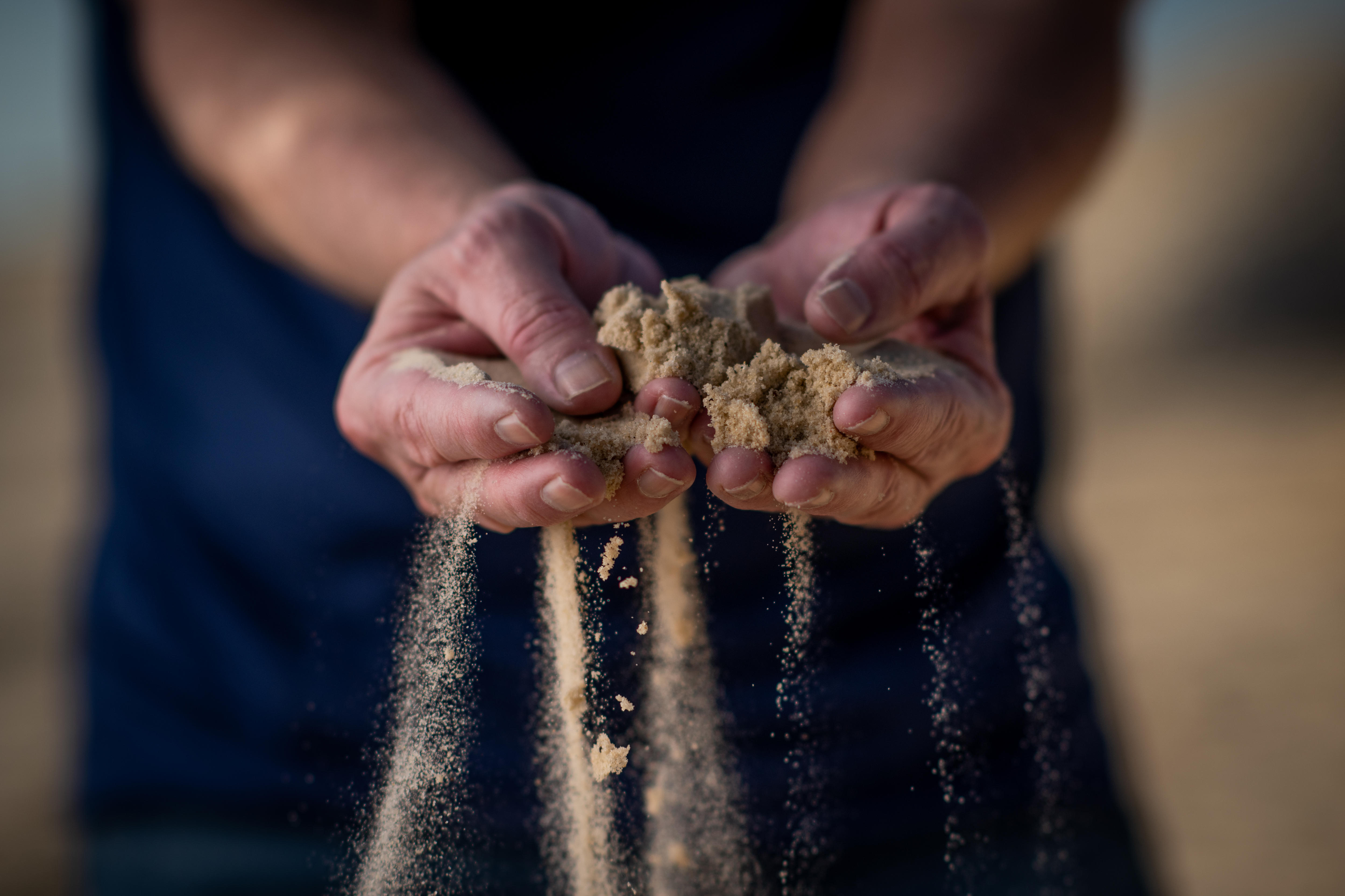 A pair of hands cupping a small amount of sand.