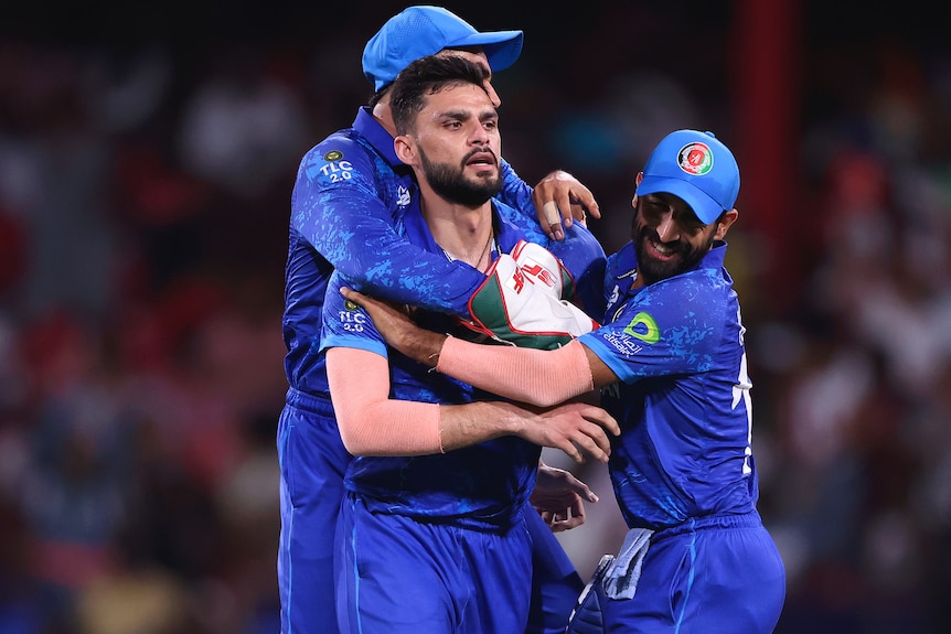 Three Afghanistan players celebrate during win over Australia.