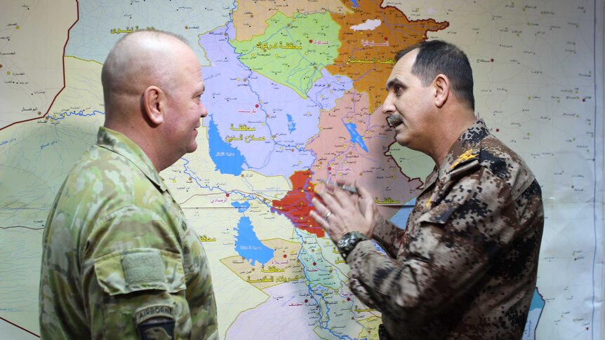 Brigadier Roger Noble speaks over a map with an officer.