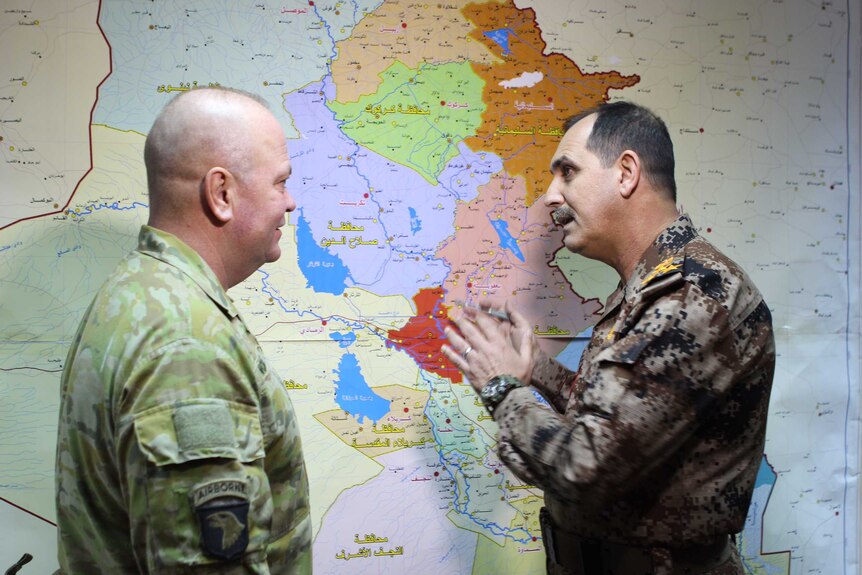 Brigadier Roger Noble speaks over a map with an officer.
