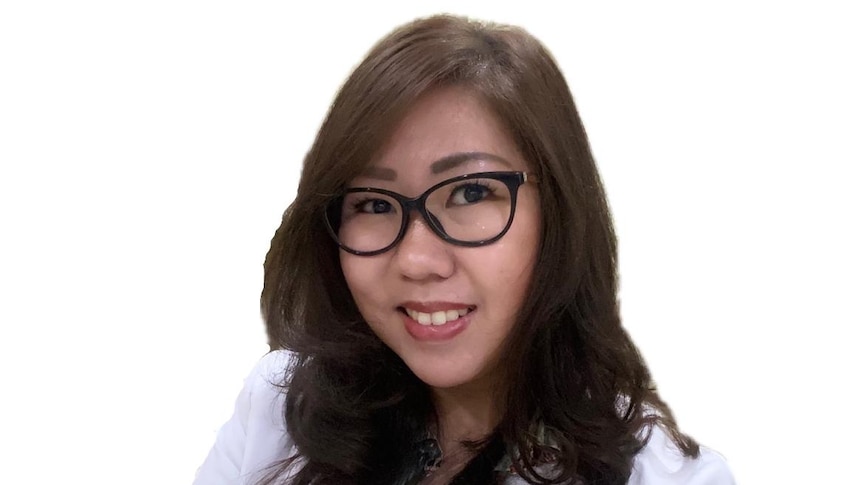 A female doctor wearing glasses and smiling to the camera