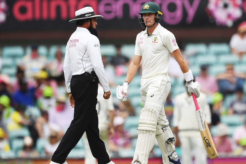 An umpire walks past a batsman during a Test at the SCG.