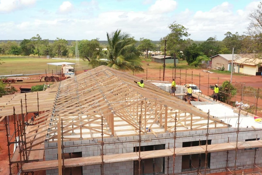 Workers are rebuilding a new home. The house is mostly built and they are finishing the rood.