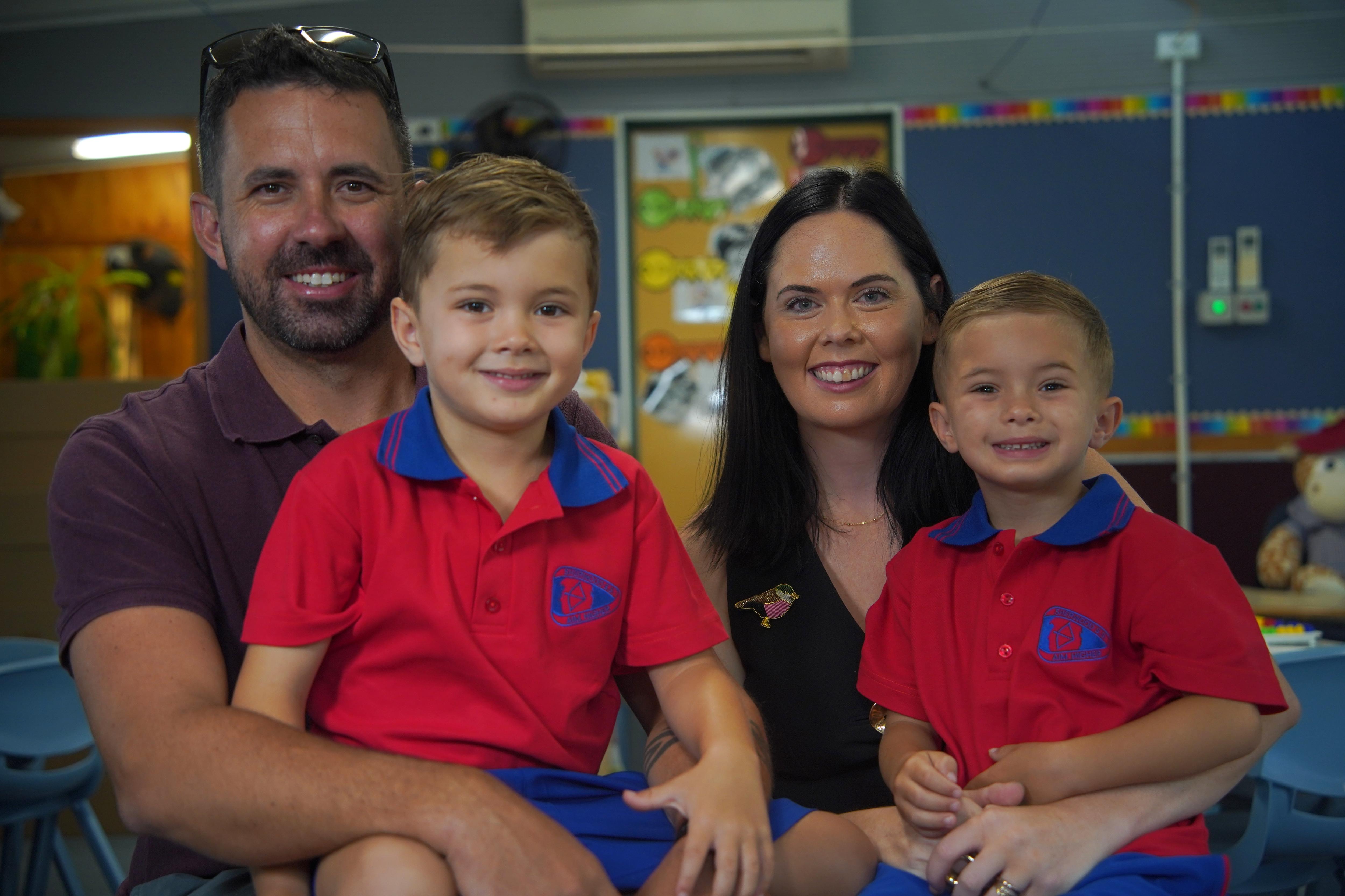 Una madre y un padre con sus dos hijos en edad escolar primaria en uniforme escolar.