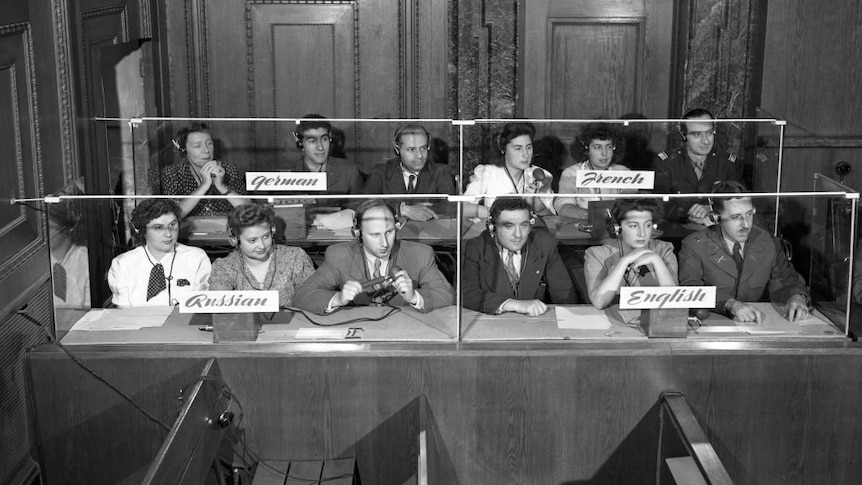 Black and white shot of group of interpreters sitting at a desk. 