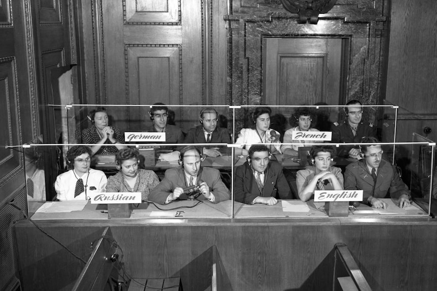 Black and white shot of group of interpreters sitting at a desk. 