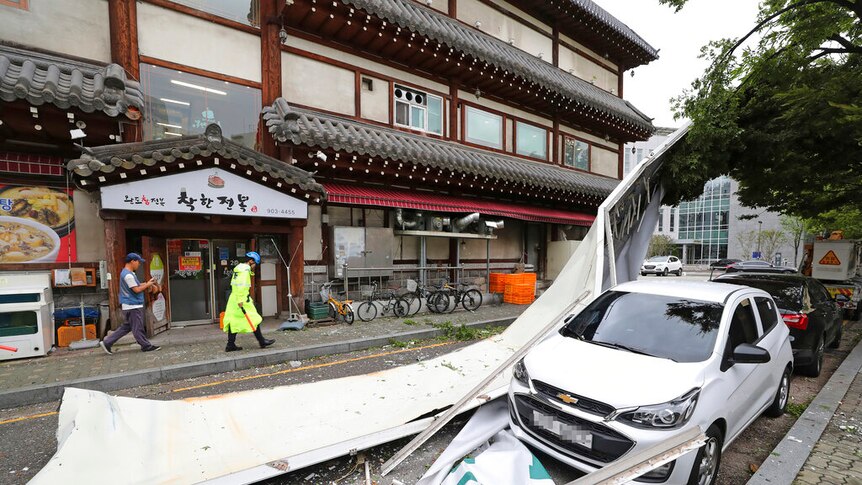 A South Korean street shows a small car hit by building debris strewn by a typhoon.