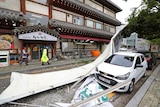 A South Korean street shows a small car hit by building debris strewn by a typhoon.