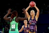 A Queensland Firebirds Super Netball player holds the ball above her head in front of a West Coast Fever defender.