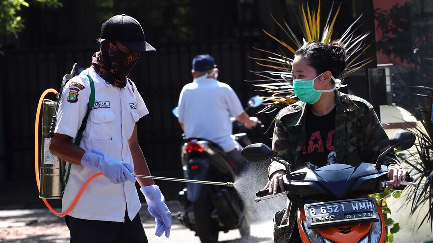 A motorist is sprayed with disinfectant to help curb the spread of coronavirus in South Tangerang, Indonesia.