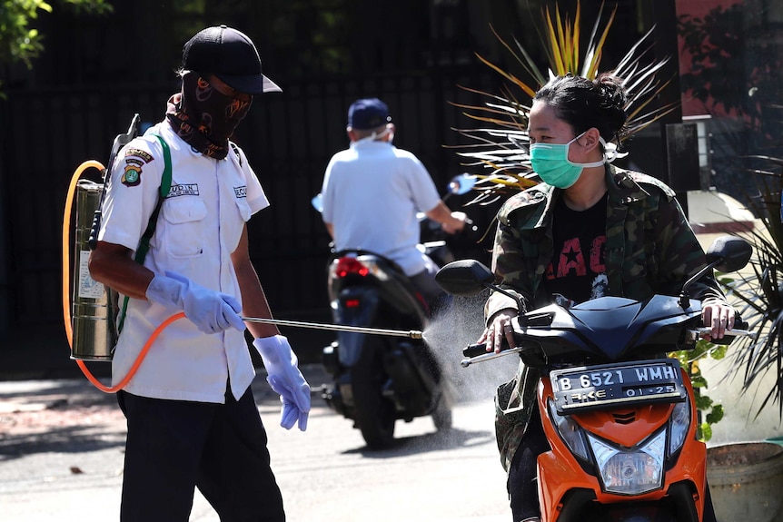 A motorist is sprayed with disinfectant to help curb the spread of coronavirus in South Tangerang, Indonesia.