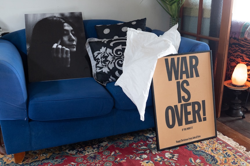 A photograph of Yoko Ono, taken by Ritchie Yorke and an original War Is Over handbill on a couch.