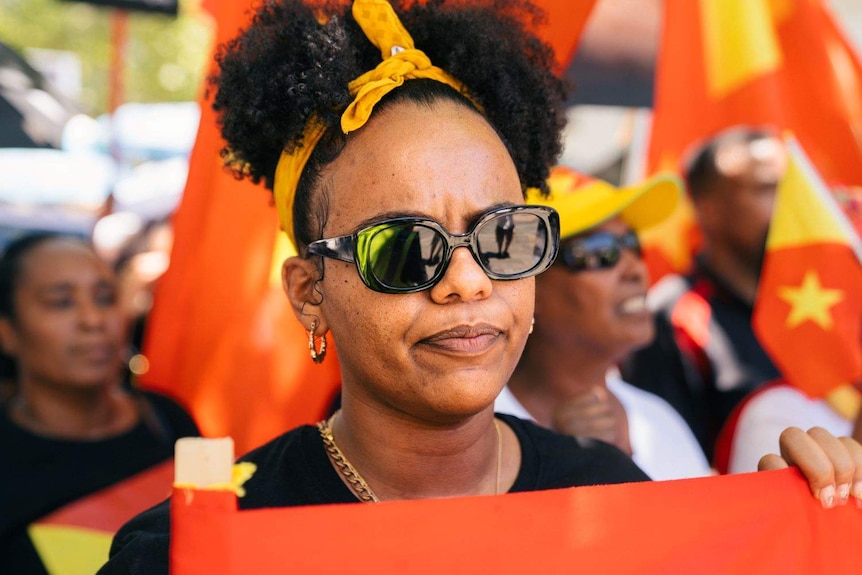 A close-up photo of Fanna Tedla at a rally with colourful flags in the background.