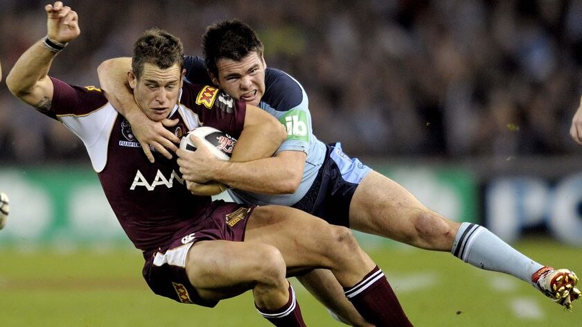 Qld player Ashley Harrison gets tackled by NSW player Jamie Lyon