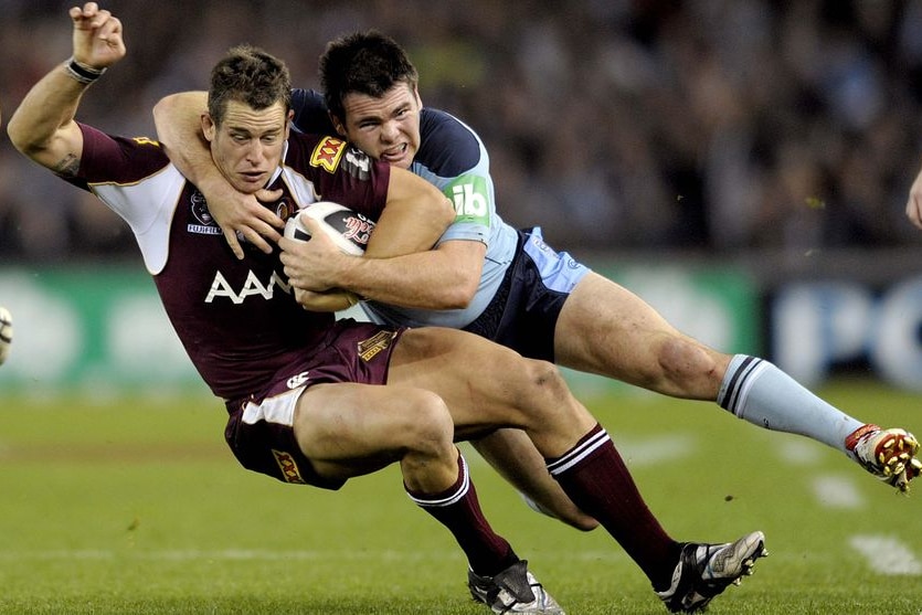 Qld player Ashley Harrison gets tackled by NSW player Jamie Lyon