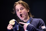 An Australian male diver points to his gold medal after winning at the World Aquatics Championships.