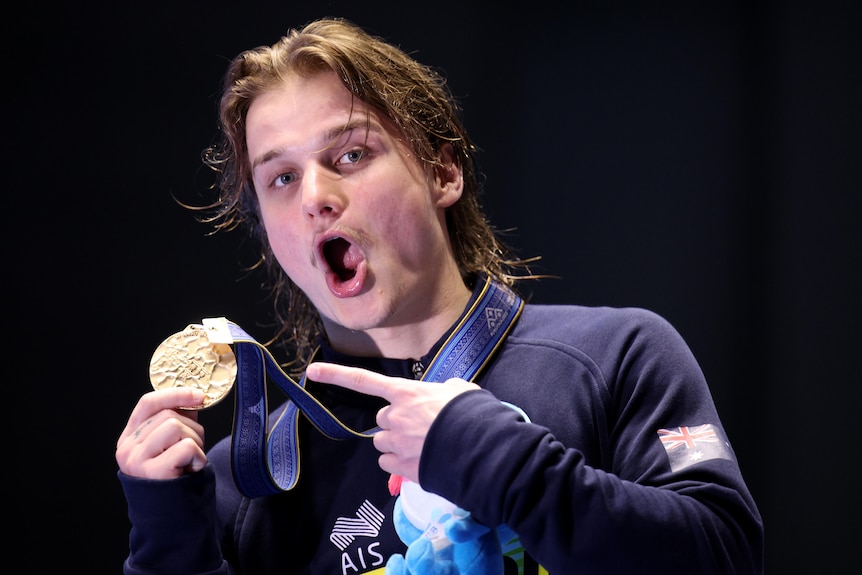 An Australian male diver points to his gold medal after winning at the World Aquatics Championships.