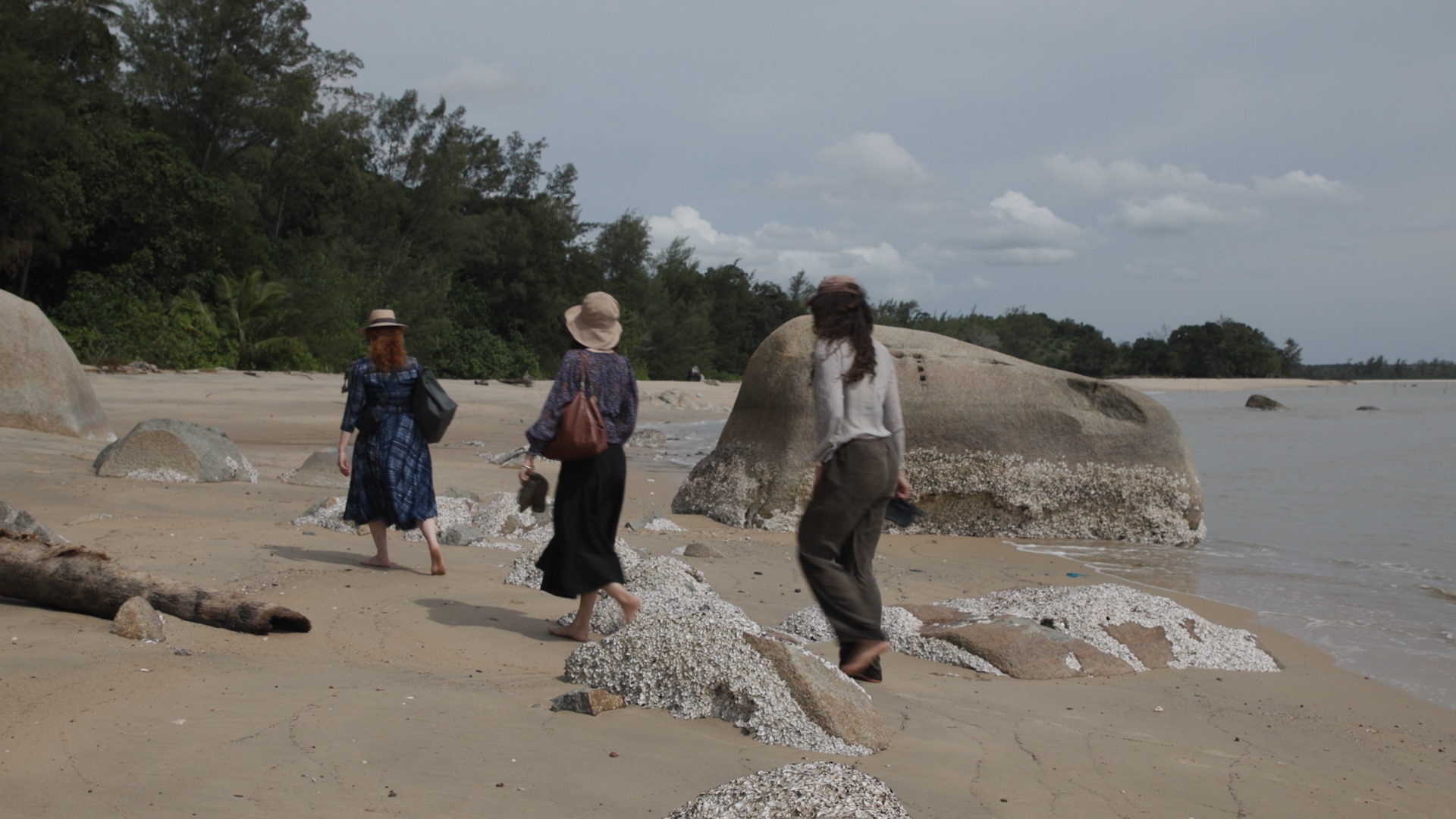 Three women on a beach walking away from the camera