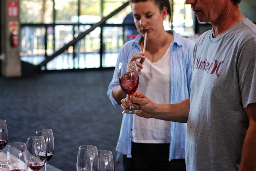 Judge Tom Carson and Melanie Chester swirl wine at the Royal Melbourne Wine Awards.