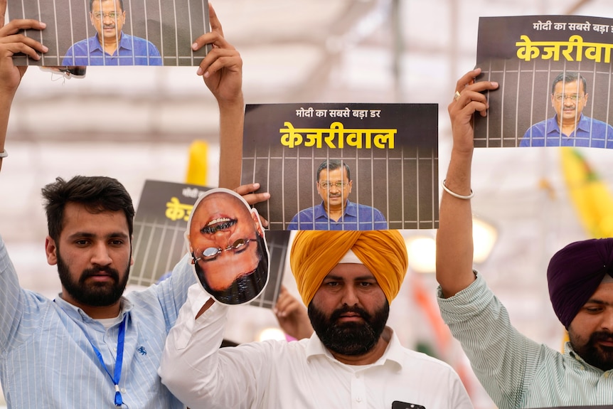 Supporters of a jailed Indian politician hold aloft pictures of the politician as they rally.