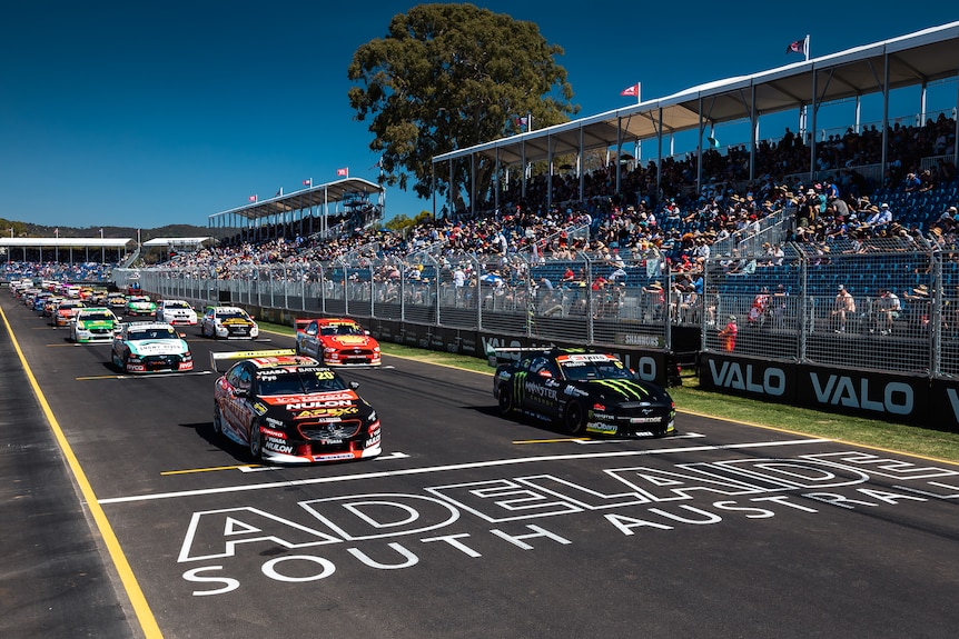 Race cars on a grid with a grandstand behind