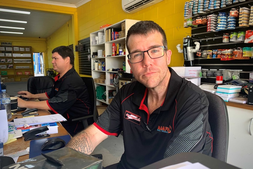 Man looks at camera, worker behind him