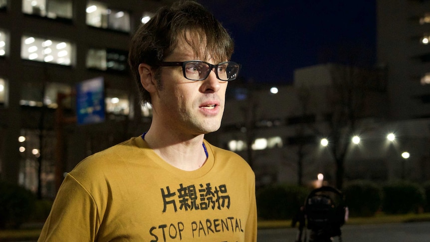 Australian journalist Scott McIntyre wears a shirt reading "STOP PARENTAL CHILD ABDUCTION".