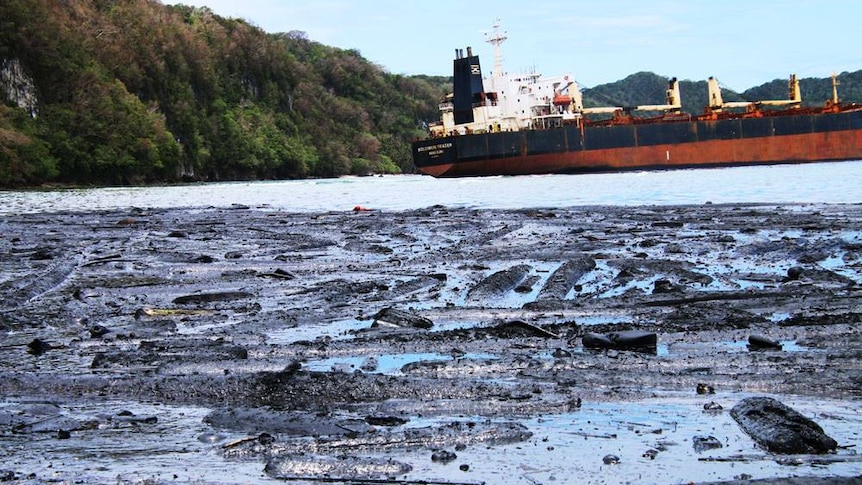 Oil covered debris sits in front of a grounded ship in the Solomon islands.