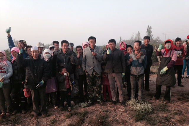 Group of warmly dressed Chinese vineyard workers giving thumbs up