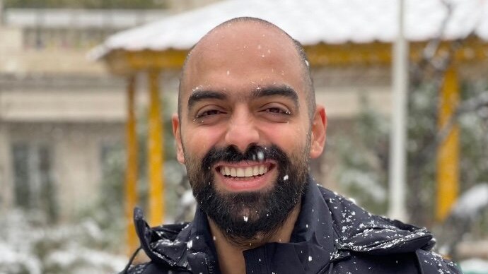 Mr Ebrahimi is smiling a black jacket with snow falling all over it. 