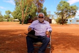 A man sitting on a camp chair on red soil