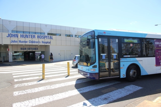 A bus drives past the entrance to the John Hunter Hospital.