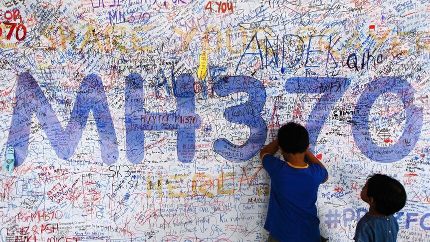 Children write on a memorial for missing flight MH370
