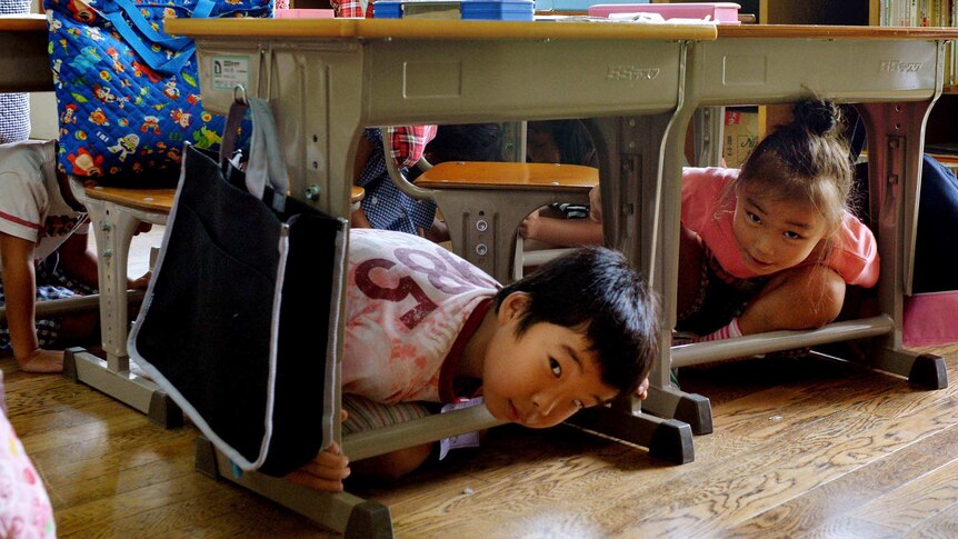 School children take cover under their desks in Tokyo