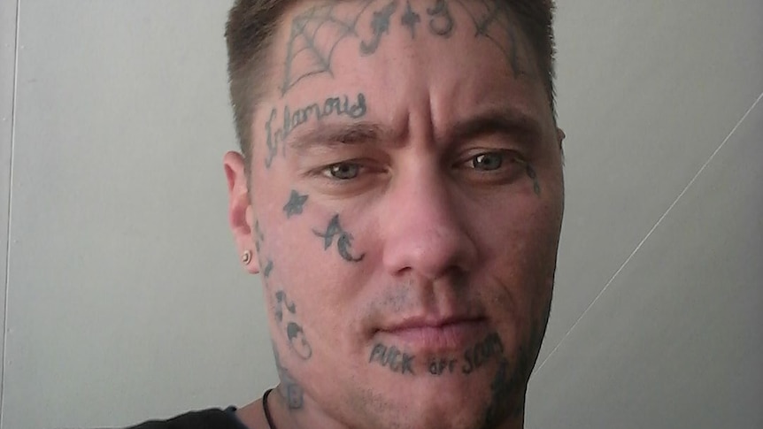 A man with short hair and face tattoos.