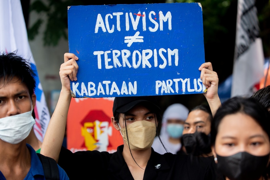 activist holds up placard that says activism does not equal terrorism