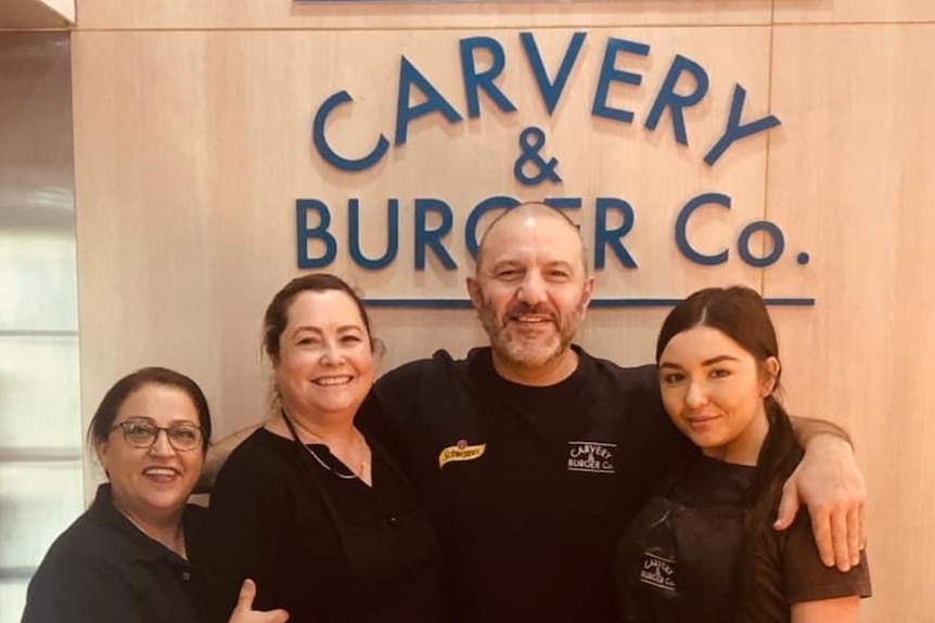 Terry Hasan stands with his workers at the Sydney food outlet he owns.